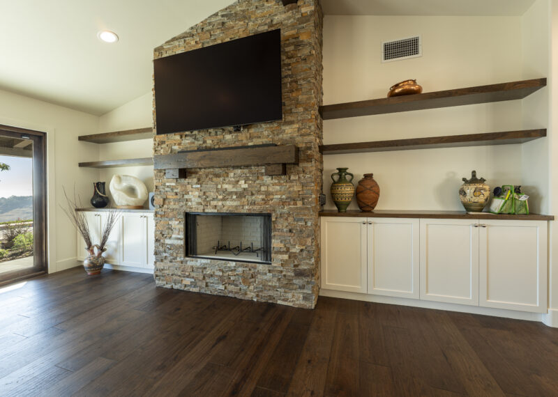 Custom stone facade fireplace and build in cabinets with wood shelves