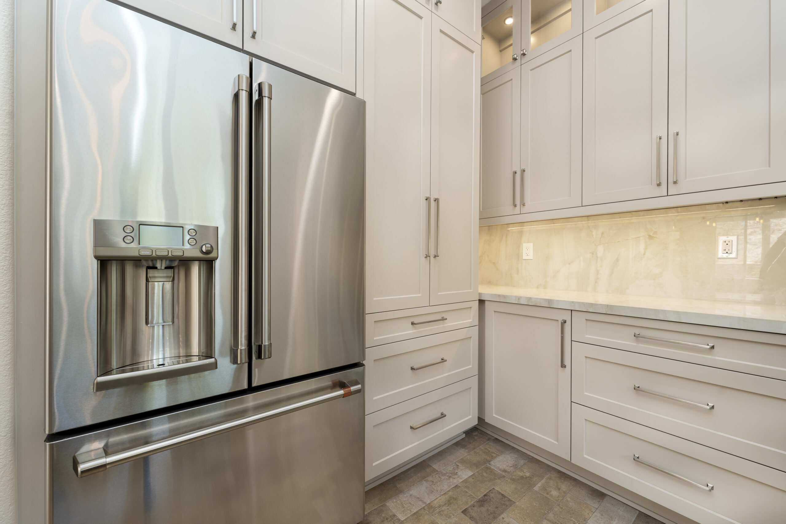 Floor to ceiling white cabinets with custom lighting and tile backsplash.